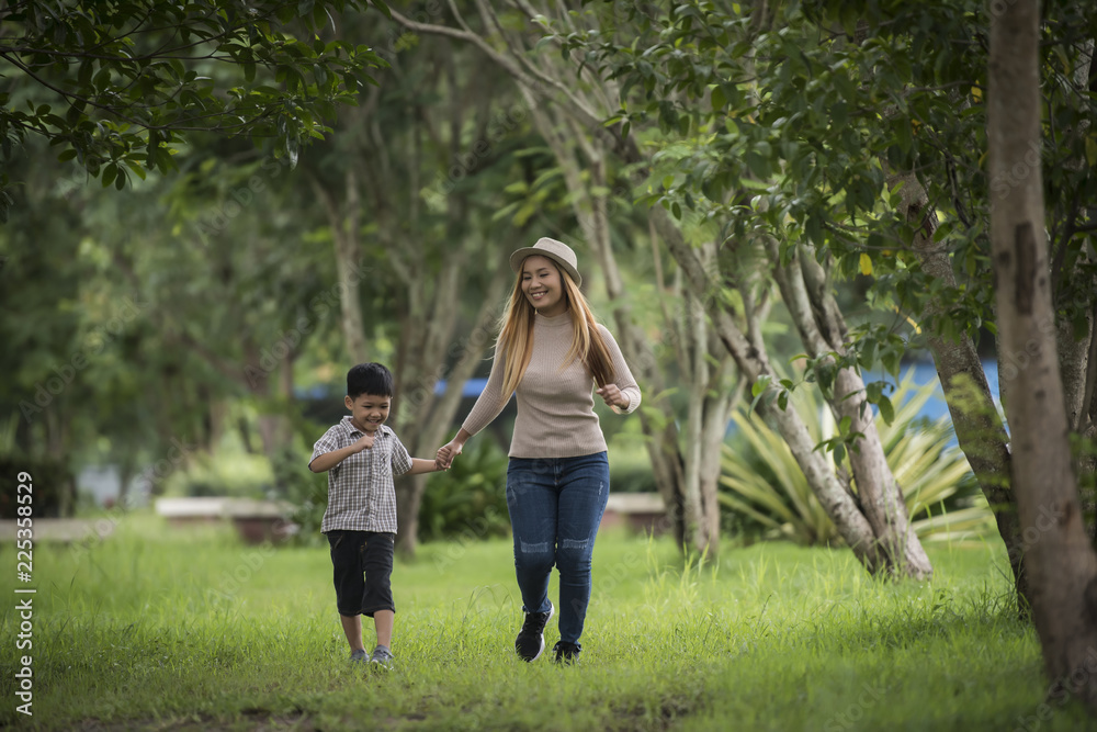 Obraz premium Portrait of mother and son happy walking together in the park holding hand. Family concept.