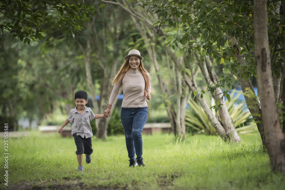 Fototapeta premium Portrait of mother and son happy walking together in the park holding hand. Family concept.