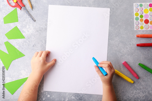 Child draws a pencil drawing empty space colorful grey background top view