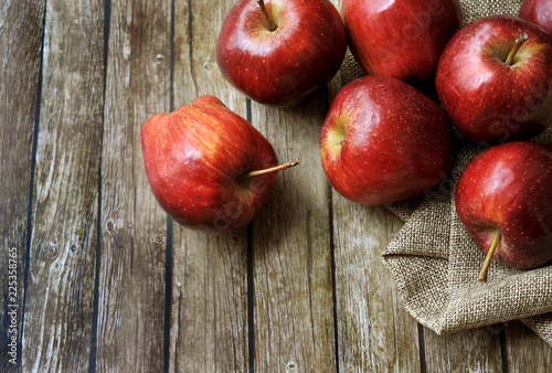 A group of fresh red apple on the wooden table with vintage sack