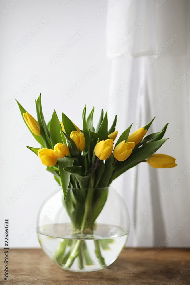 A bouquet of yellow tulips in a vase on the windowsill. A gift t A bouquet of yellow tulips in a vase on the windowsill. A gift t