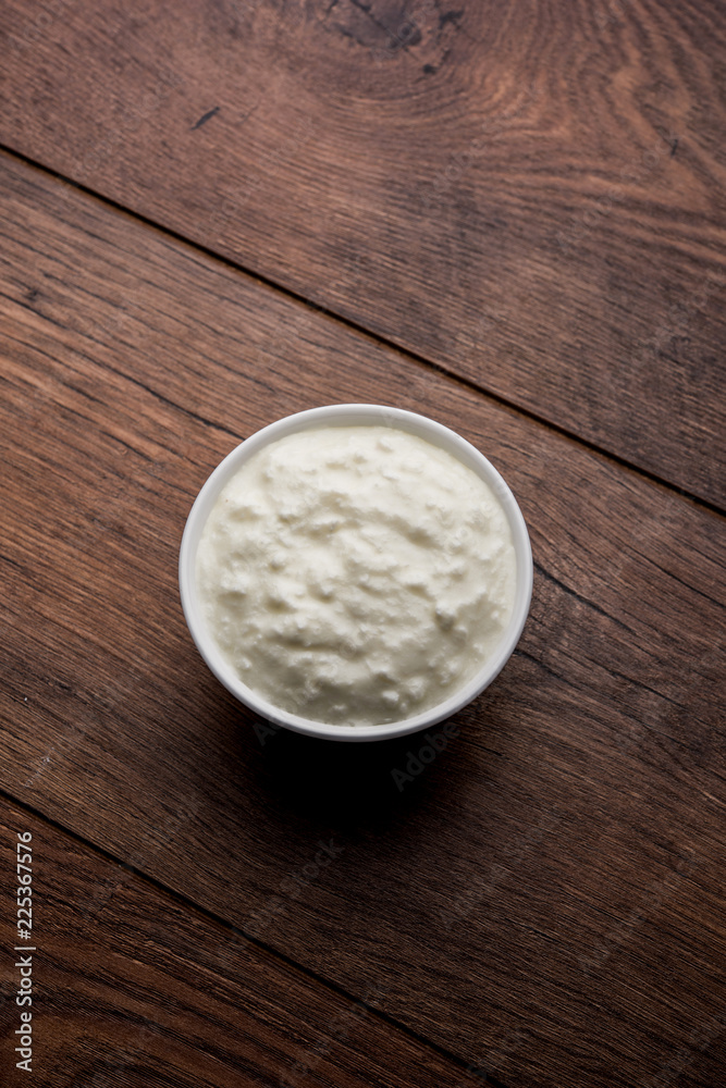 Plain curd or yogurt or Dahi in Hindi, served in a bowl over moody background. Selective focus Plain curd or yogurt or Dahi in Hindi, served in a bowl over moody background. Selective focus