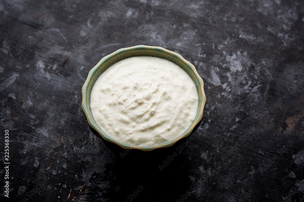 Plain curd or yogurt or Dahi in Hindi, served in a bowl over moody background. Selective focus Plain curd or yogurt or Dahi in Hindi, served in a bowl over moody background. Selective focus