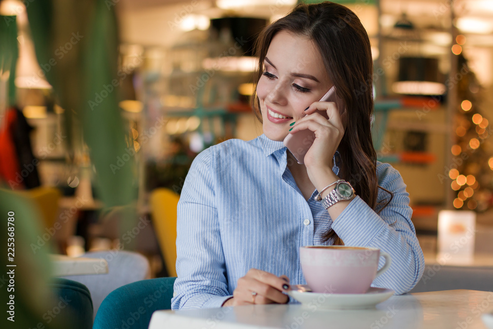 Beautiful cute caucasian young woman in the cafe, using mobile phone and drinking coffee smiling Beautiful cute caucasian young woman in the cafe, using mobile phone and drinking coffee smiling