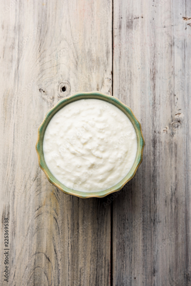 Plain curd or yogurt or Dahi in Hindi, served in a bowl over moody background. Selective focus Plain curd or yogurt or Dahi in Hindi, served in a bowl over moody background. Selective focus
