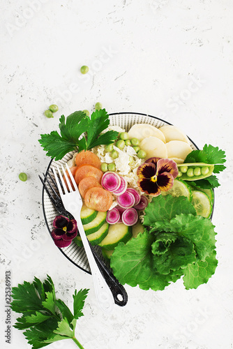 Vegetables summer fruit detox bowl. Vegetarian healthy food. Salads, lettuce leaves, raspberries, green peas, cucumber, carrots, daikon, edible flowers Top View.