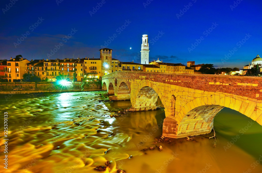 View of the historic city center along Adige river at night in Verona, Italy.