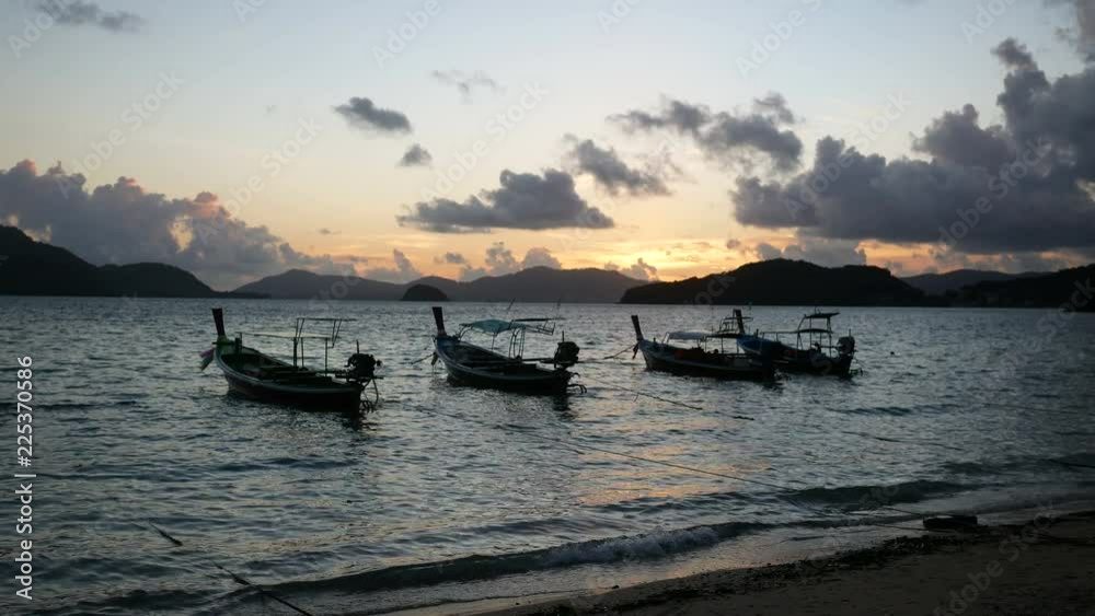moving silhouette long tail fishing boat in sea wave with beautiful cloudy blue golden twilight sky background in evening sunset time and silhouette mountain in long distance moving silhouette long tail fishing boat in sea wave with beautiful cloudy blue golden twilight sky background in evening sunset time and silhouette mountain in long distance
