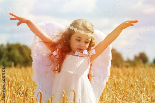 Девочка - ангел с крыльями, летающая по полю photo