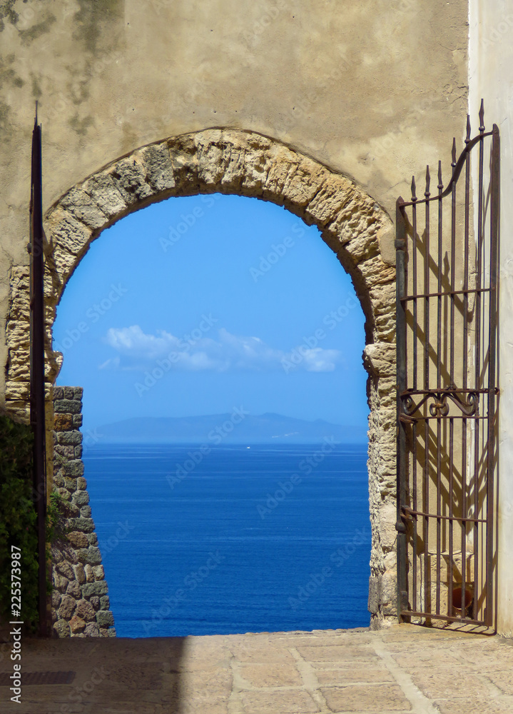Open gate showing a marvelous view on the mediterranean sea, blue sky and blue ocean, Cala Spinosa, Sardinia, Italy 