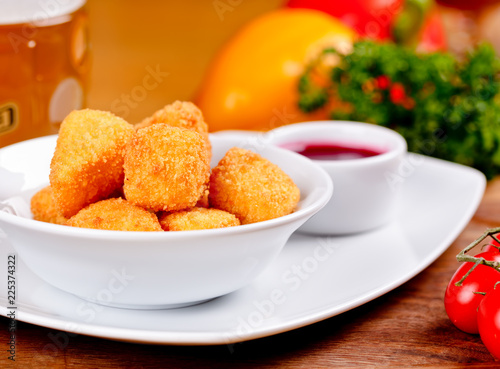 Deep fried cheese with berry sauce on white plate. Close up
