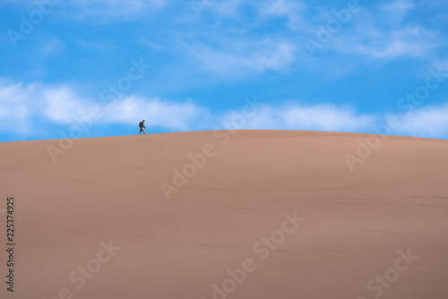 Man walking along top of sand dunes
