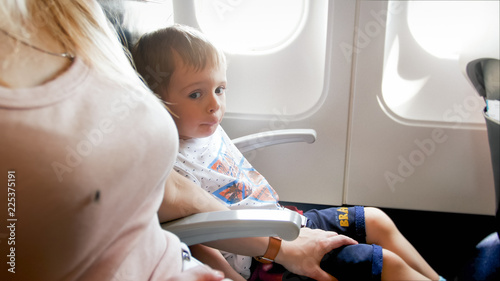Young caring mother calming her toddler son scared of flight in airplane
