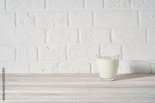 Glass of milk on white wooden background.