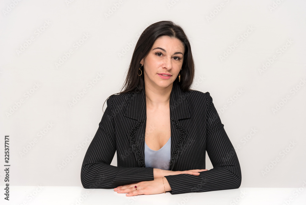 Portrait of a beautiful brunette woman on a white background with different emotions sitting at the table. Portrait of a beautiful brunette woman on a white background with different emotions sitting at the table.
