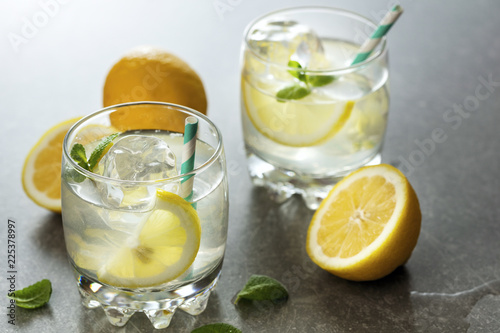 two glasses of fresh lemonade on gray background