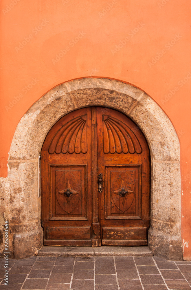 old wooden door orange wall background and stone arch