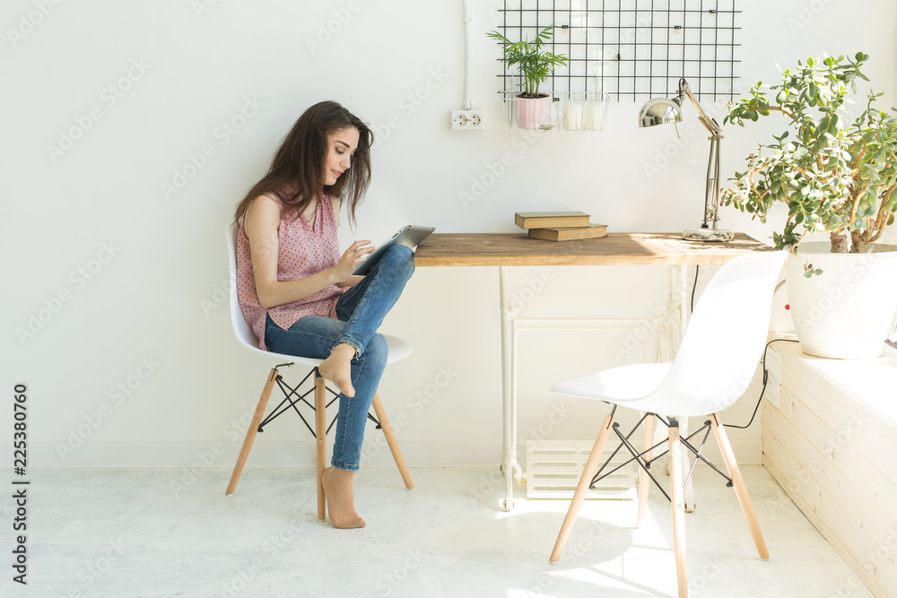 People, technology and internet concept - young woman using digital tablet at home