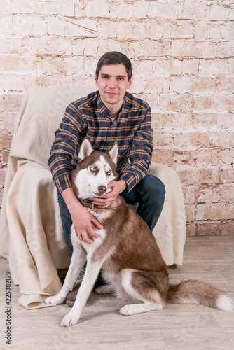 A man and a hussy dog are posing in the studio. The basics of training pets.