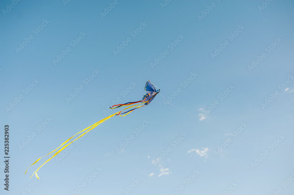 Multi-colored kite against the background of the blue sky Multi-colored kite against the background of the blue sky