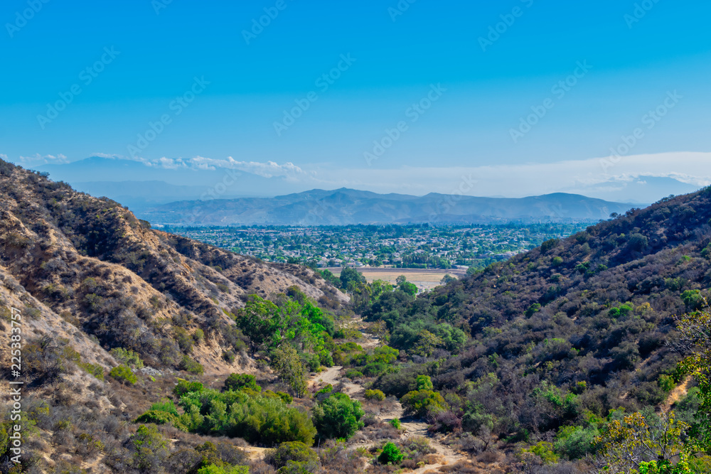Fototapeta premium Suburbs in the distance with mountain hiking trails and room for text in sky