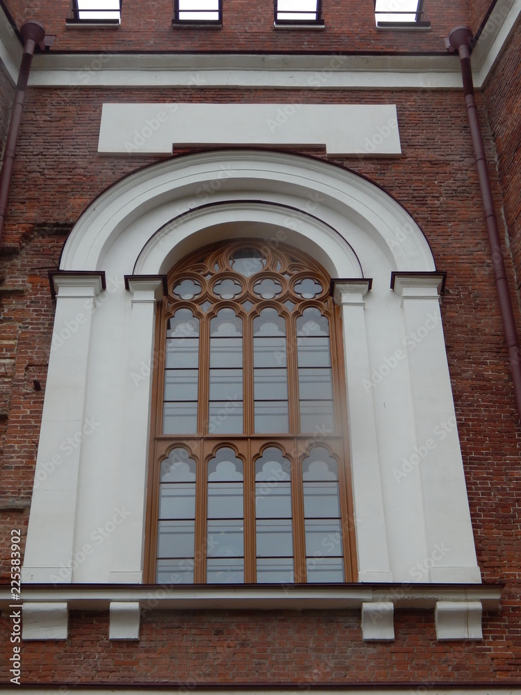 Beautiful old window in the Gothic style on the wall of red brick Beautiful old window in the Gothic style on the wall of red brick