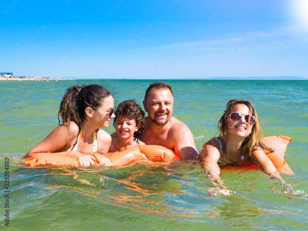 happy family with children is swimming and having fun in the sea on an inflatable mattress. happy friendly family concept happy family with children is swimming and having fun in the sea on an inflatable mattress. happy friendly family concept