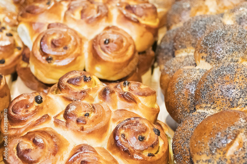 Fresh baked pastries - buns with raisins and roll with poppy seeds, as a background