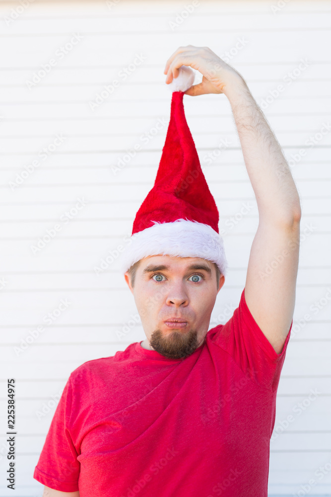 Holidays, christmas and clothing concept - surprised funny handsome man in santa hat posing on white background Holidays, christmas and clothing concept - surprised funny handsome man in santa hat posing on white background