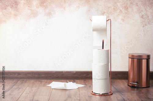 Toilet paper holder with rolls on floor indoors. Space for text