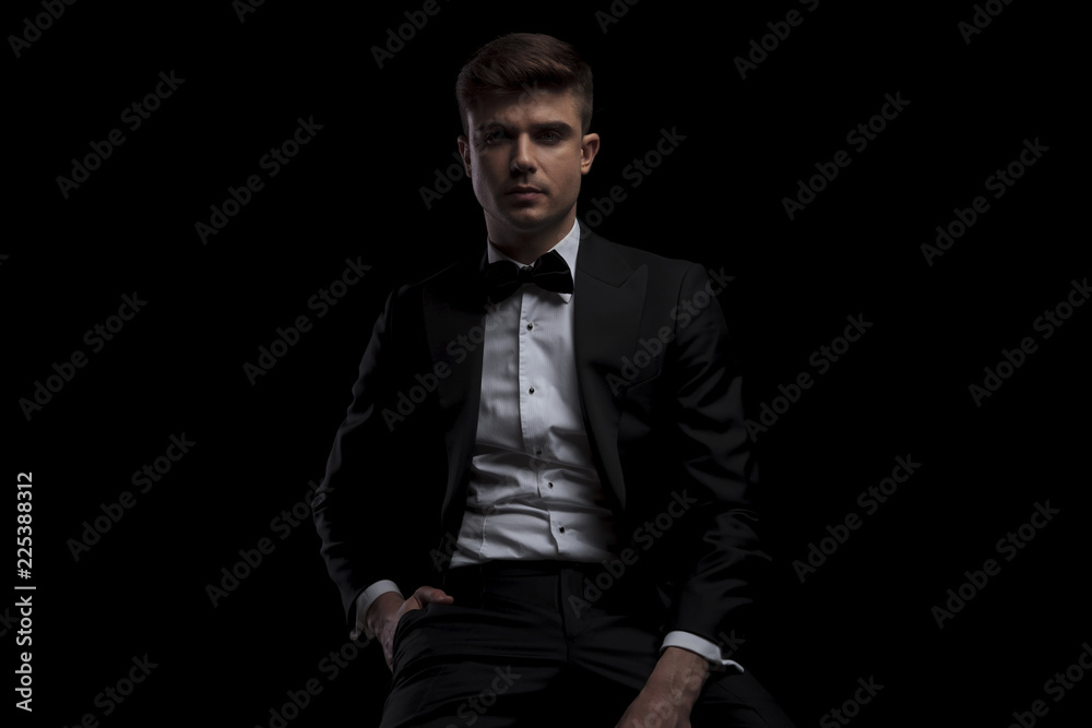 portrait of relaxed seated man wearing a black suit