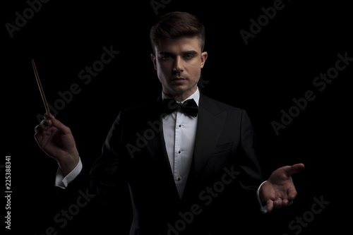 portrait of elegant perfomer conducting a concert with a baton photo