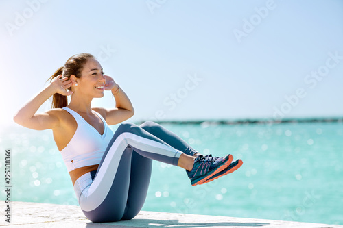 Fit latina girl doing abs next to the Beach