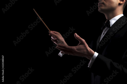 portrait of young orchestra conductor performing with a baton photo