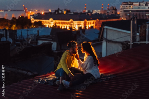 Loving couple is sitting on the roof of the house.