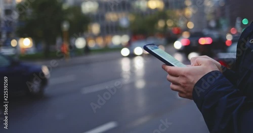 Young Man Hands Using Smartphone in the City. SLOW MOTION 4K. Unrecognizable Man using cell phone app, standing on busy street during rush hour traffic. Social network, planning, communicating.