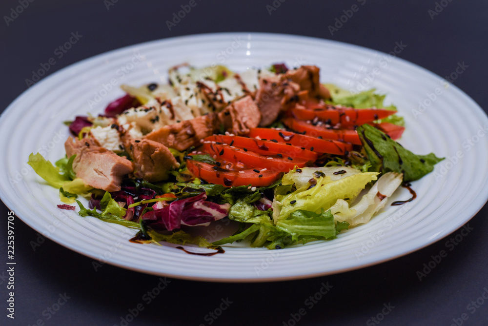Meat salad with tomato served in white plate on dark table. Copy space Meat salad with tomato served in white plate on dark table. Copy space