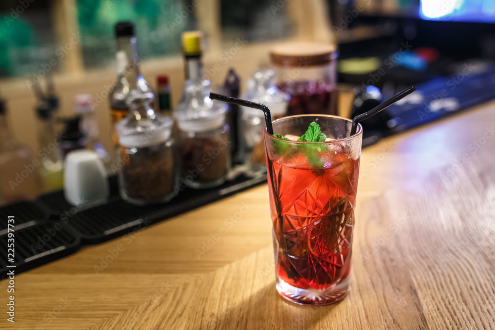 red cocktail in a glass with mint and two tubes on a table in a luxury bar red cocktail in a glass with mint and two tubes on a table in a luxury bar