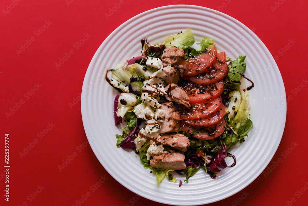 Meat salad with tomato served in white plate on dark table. Copy space Meat salad with tomato served in white plate on dark table. Copy space