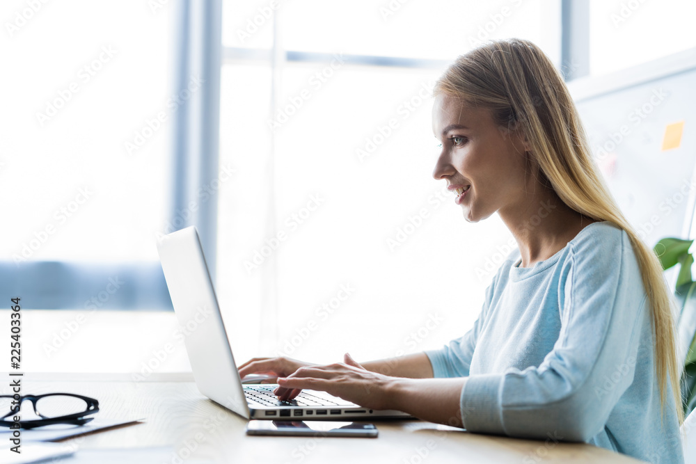 New solution every day. Confident young woman in smart casual wear working on laptop while sitting at her working place in office. New solution every day. Confident young woman in smart casual wear working on laptop while sitting at her working place in office.