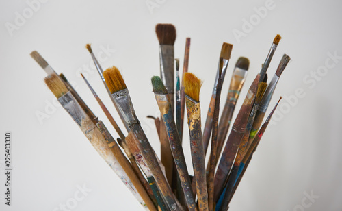 Various dirty paint brushes in a black cup isolated on white background with copy space, close-up. Colorful paintbrushes and artistic Paint Tools 