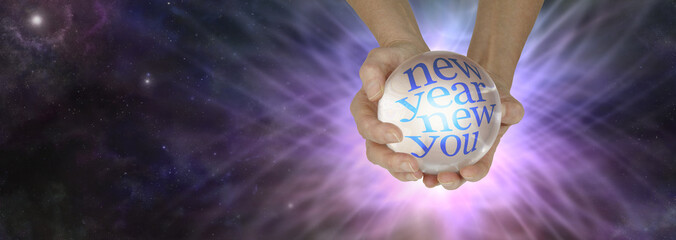 Find out what the New Year holds with a crystal ball reading - female holding crystal ball showing NEW YEAR NEW YOU against a lilac pink web formation and dark night sky with copy space
