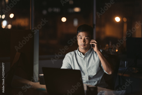 Asian businessman talking on a cellphone in a dark office