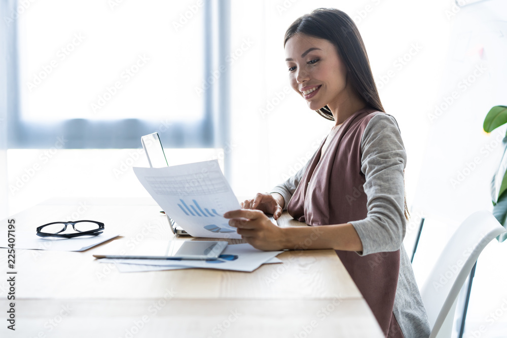 New solution every day. Confident young woman in smart casual wear working on laptop while sitting at her working place in office. New solution every day. Confident young woman in smart casual wear working on laptop while sitting at her working place in office.