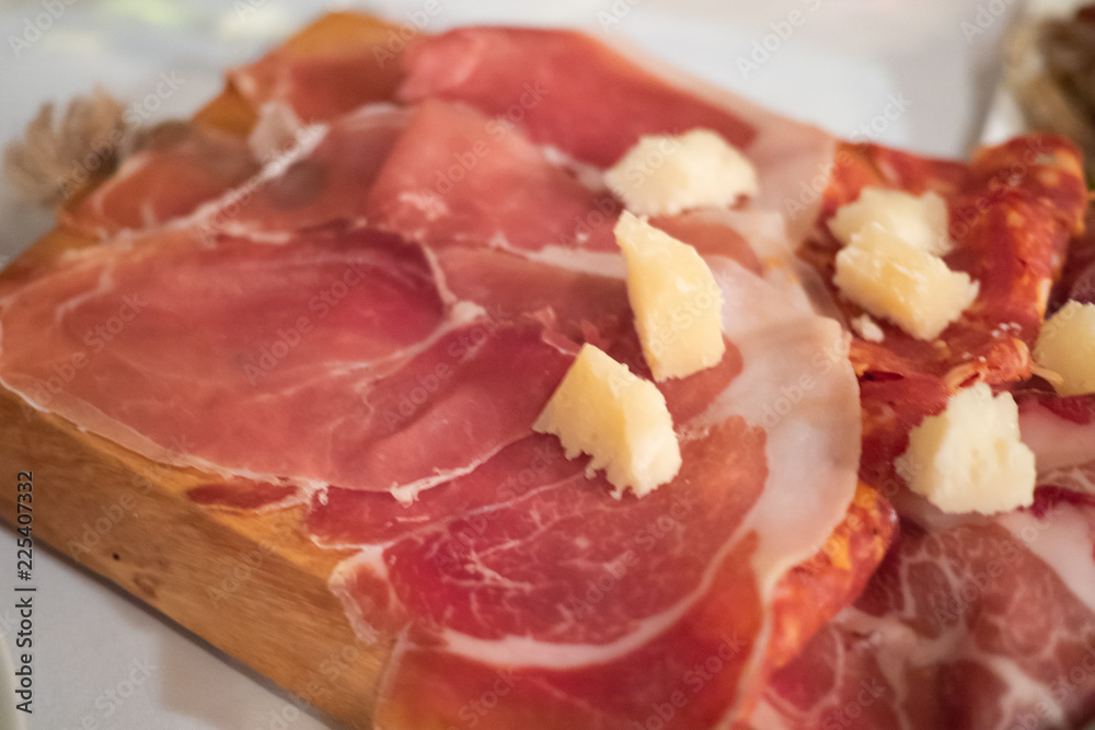 Assortment of tasty and delicious Italian antipasto delicatessen. Parma ham and Salami sausage and cold cut with cheese on wooden board. A perfect appetizer, party snack, or good accompany with wine