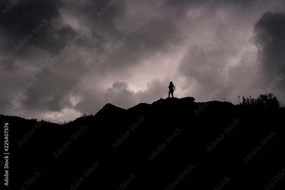 girl silhouette on a hill with dark clouds