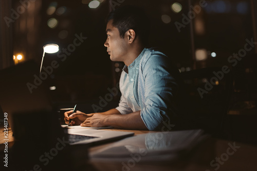 Young Asian businessman working online in a dark office