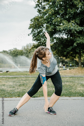 A young and beautiful girl doing outdoor sports. In the park the girl performs sports exercises. © ibilyk13