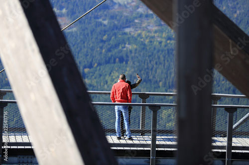 Para młodych ludzi na tarasie widokowym nad przepaścią w górach, selfie.