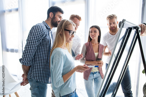 Group of young colleagues dressed casual standing together in modern office and brainstorming.